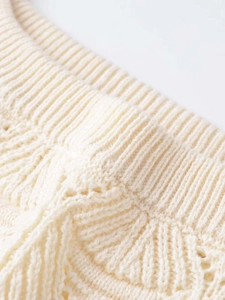 Macro shot of cable knit texture and ribbed edge on a creamy white knitted sweater