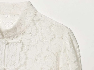 Detailed view of mandarin collar and traditional knot buttons on white lace blouse