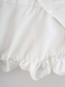 Gros plan détaillé du tissu brodé blanc avec un élégant ourlet à volants et motif de feuilles