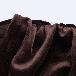 Détail macro du tissu en velours plissé de la robe café foncé montrant texture et éclat