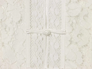 Close-up of intricate white lace fabric texture with traditional Chinese knot button detail