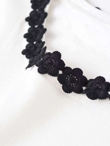 Close-up of black floral embroidery on white knit fabric highlighting the craftsmanship