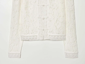 Detail of elegant white lace shirt showing intricate floral patterns and Chinese frog buttons