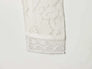 Close-up detail of white lace floral embroidery and hollowed-out fabric on the sleeve cuff