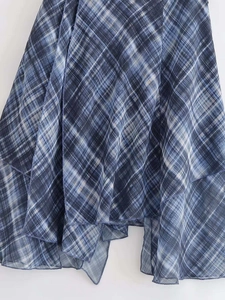 Détail d'une jupe midi à carreaux bleus avec ourlet asymétrique et multicouche