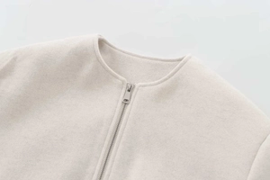 Detail of oat-beige wool blend bomber jacket showing silver metal zipper and soft fabric texture