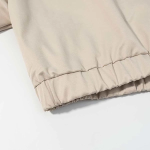 Detailed close-up of beige cotton jacket with elasticated hem and neat stitching
