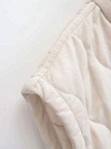 Detailansicht der beigen Steppweste mit feinem Rautenmuster und Twill-Gewebe-Struktur