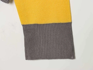 Detail of yellow and grey striped knit sweater with fine stitch and ribbed cuffs