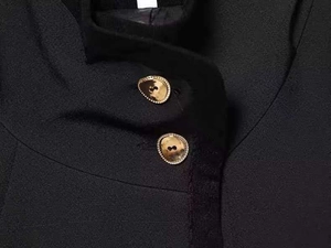 Detailed macro view of gold irregular metal buttons on black tailored jacket fabric