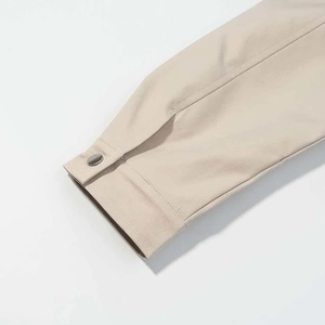 Detailed close-up of light apricot jacket cuff with fine twill texture and metal snap button