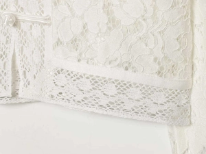 Detail of white lace shirt featuring an intricate Chinese frog button and scalloped hem