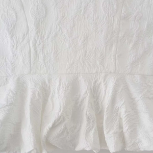 Haut blanc sans manches d'été avec tissu texturé et design de l'ourlet à volants
