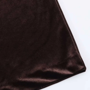 Détail du tissu en velours marron foncé montrant la texture lisse et les coutures de l'ourlet