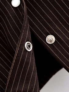 Detailed macro view of white pinstripe fabric and silver metal snap buttons on a cardigan