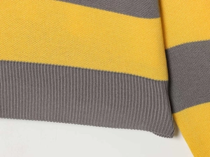 Detailed close-up of yellow and grey striped knit sweater with ribbed hem texture