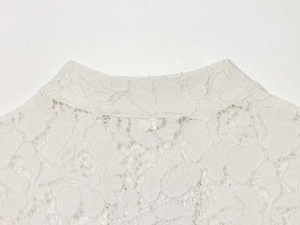 Close-up of white lace shirt featuring a mock neck and intricate floral hollow details