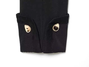 Macro detail of black jacket sleeve with gold irregular buttons and logo engraving