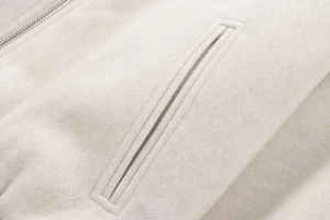 Detailed macro shot of soft ivory bomber jacket with side pocket and metallic zipper