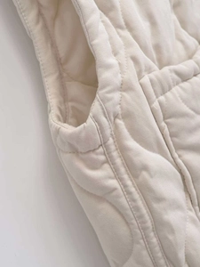 Detailansicht der Rautensteppung und Nähte der cremefarbenen Weste aus Twill-Stoff