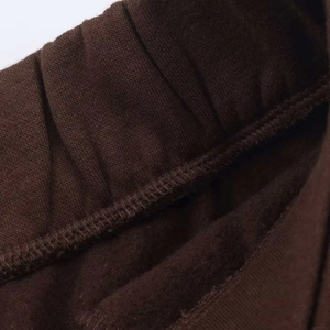 Detail view of dark brown joggers featuring ribbed elastic waistband and fleece lining