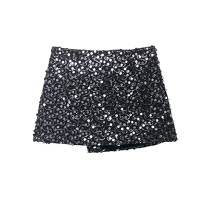 Close-up of black mini skirt featuring intricate silver sequin swirls and asymmetric hem