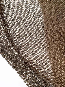 Macro view of bronze metal mesh knit fabric with precise interlocking ring texture