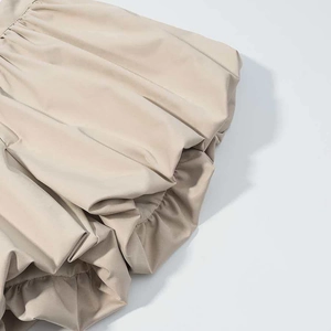 Detail of beige bubble skirt featuring intricate pleated texture and soft woven fabric