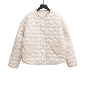 Detail of beige quilted jacket showing unique heart-shaped stitching and front pockets