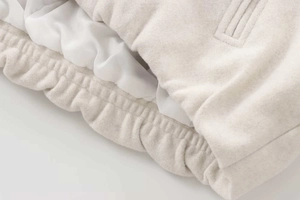 Detailed close-up of apricot wool bomber jacket featuring ribbed hem and smooth inner lining