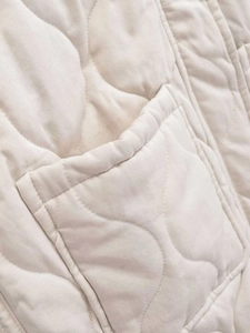Detailaufnahme der beigen Weste mit Wellensteppung, Köperbindung und aufgesetzter Tasche