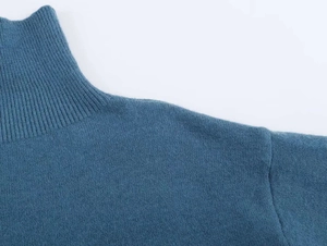 Detail of blue high-neck knitted sweater showing ribbed collar texture and shoulder seam