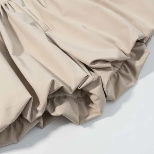 Detail of elegant beige pleated ruffles and silky fabric texture on the stylish skirt hem
