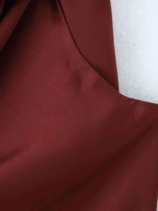 Gros plan du tissu bordeaux de la robe midi montrant les détails de couture et texture