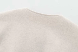 Detailed macro shot of premium beige wool fabric texture and clean stitching on jacket