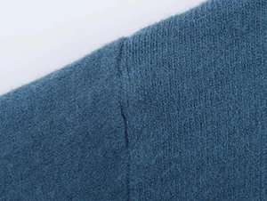 Detail showing the flat shoulder seams and soft texture of this dark teal knit sweater