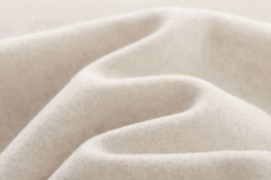 Macro shot showing soft oatmeal wool fabric texture and fine fiber details of the jacket
