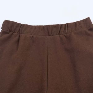 Detail of dark brown elastic waistband with precise stitching on tapered trousers