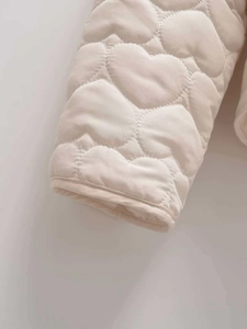 Detail of cream jacket cuff featuring 3D heart-shaped quilting and premium stitching