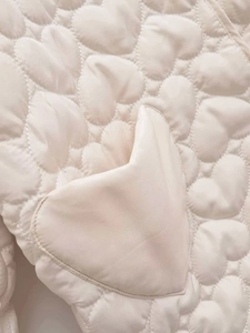 Close-up of beige quilted jacket featuring unique heart pattern and matching heart pocket