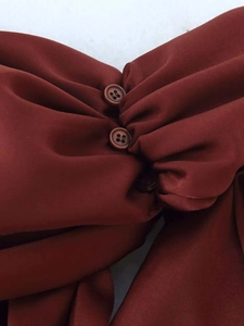 Détail d'une robe midi en satin rouge rouille avec fronces élégantes et petits boutons assortis