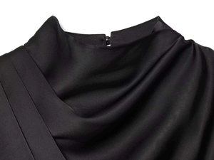 Detailed view of black satin blouse featuring elegant pleated neckline and button closure