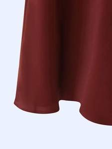 Détail de l'ourlet asymétrique de la robe rouge foncé avec une finition soignée