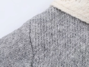 Close-up of gray knit fabric and cream-colored openwork texture on the shoulder seam