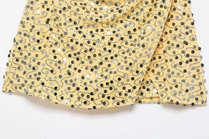 Macro shot of yellow fabric with silver and black sequin embroidery on mini skirt hem