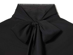 Detail of elegant black pleated chiffon shirt featuring high collar and large bow tie