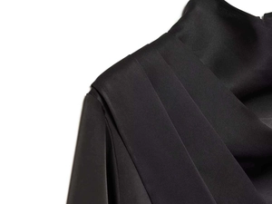 Detailed close-up of pleated shoulder design on a black satin long-sleeved shirt