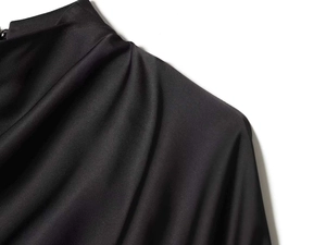 Detail of elegant black satin shirt with stand collar and graceful shoulder pleats