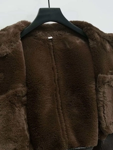 Detail of soft faux fur texture and internal stitching on a dark brown winter coat