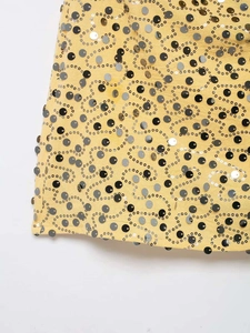 Detailed macro view of vibrant yellow mini skirt featuring swirling sequin embroidery